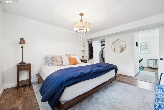 bedroom with baseboards, a closet, wood finished floors, and a chandelier