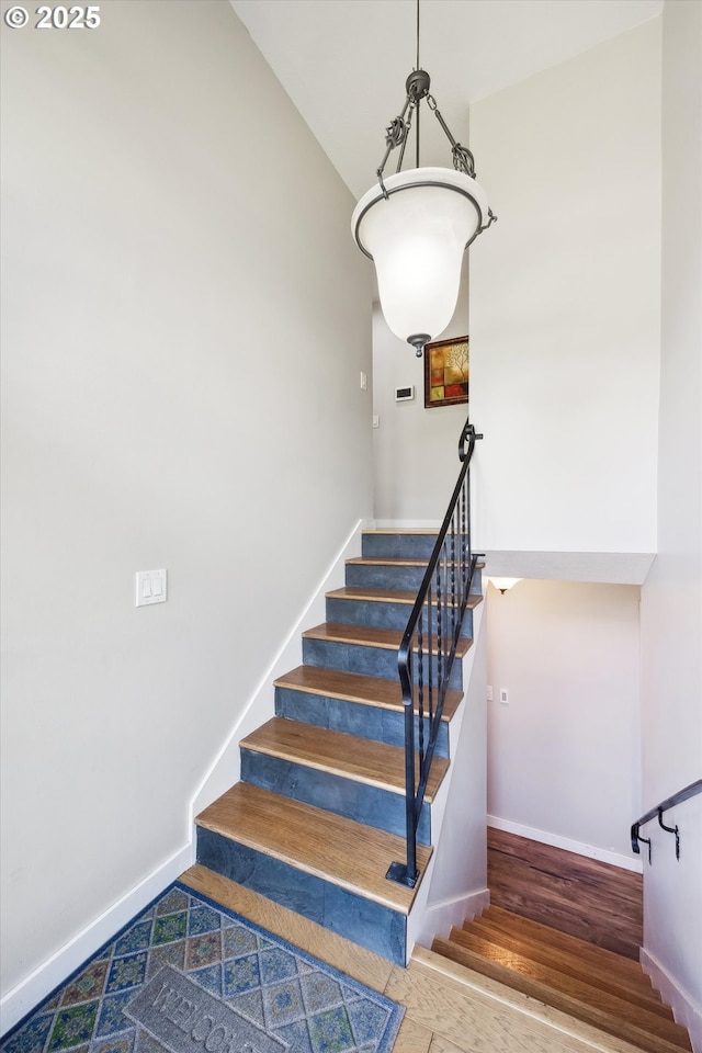 stairs with baseboards, wood finished floors, and vaulted ceiling