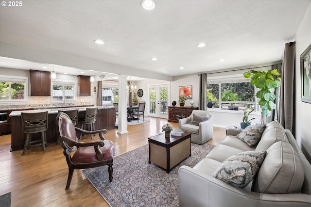 living area with recessed lighting, a textured ceiling, decorative columns, and light wood-type flooring