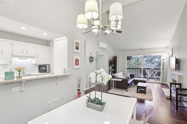 dining room with high vaulted ceiling, sink, dark wood-type flooring, and an inviting chandelier