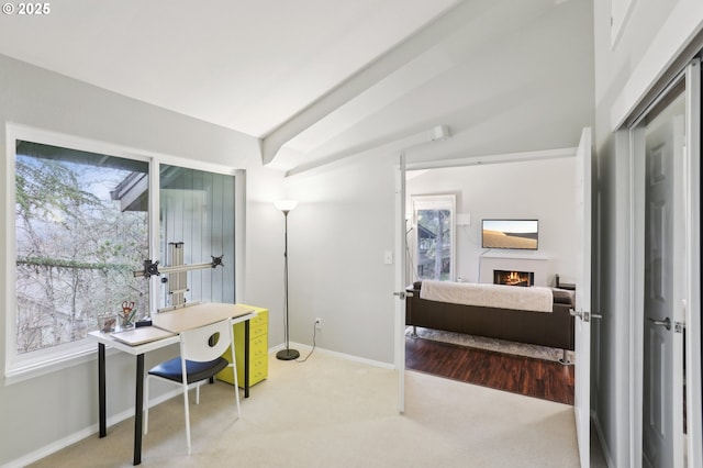 home office featuring a wall mounted air conditioner, lofted ceiling, healthy amount of natural light, light colored carpet, and baseboards