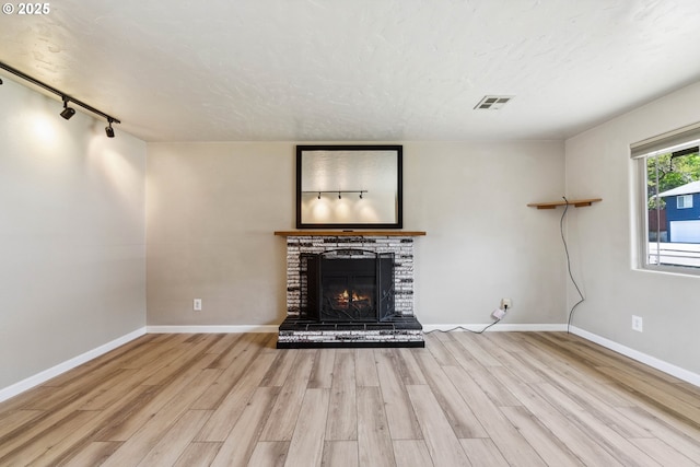 3840 Vista Dr, North Bend, OR 97459 - unfurnished living room featuring wood finished floors, a fireplace, rail lighting, and a textured ceiling