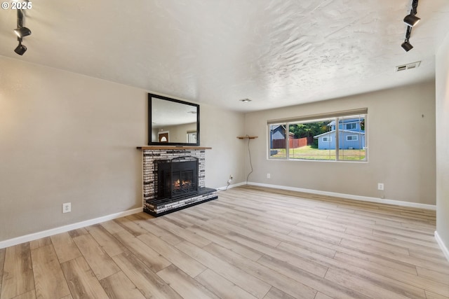 3840 Vista Dr, North Bend, OR 97459 - unfurnished living room featuring track lighting, wood finished floors, a brick fireplace, and a textured ceiling