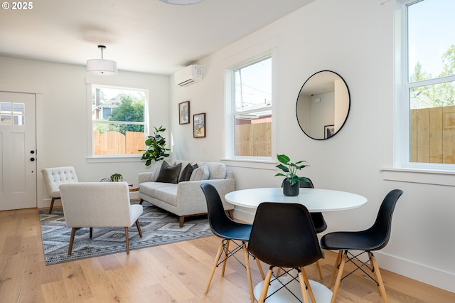dining area featuring light wood-style floors, baseboards, and a wall mounted AC