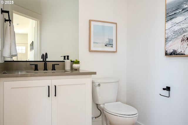 half bath featuring vanity and toilet
