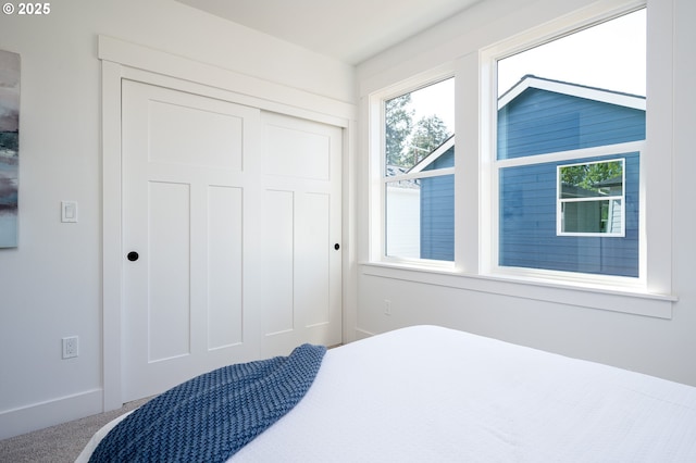 bedroom with carpet floors, baseboards, and a closet