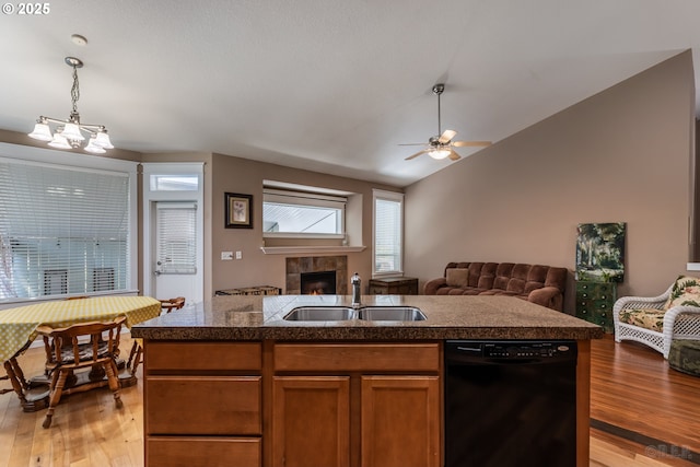 kitchen with a sink, a tiled fireplace, black dishwasher, open floor plan, and light wood-type flooring