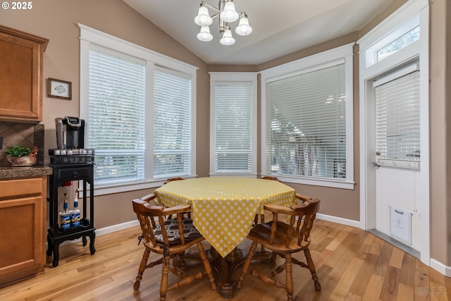 dining room with baseboards, a notable chandelier, light wood-style flooring, and lofted ceiling