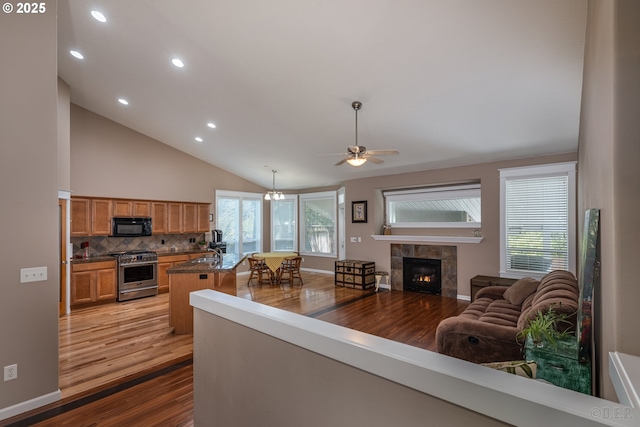 living room featuring wood finished floors, ceiling fan, recessed lighting, a tiled fireplace, and vaulted ceiling