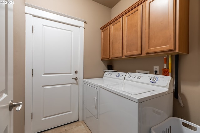 laundry area featuring separate washer and dryer, cabinet space, and light tile patterned floors