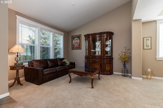 carpeted living area with baseboards and lofted ceiling