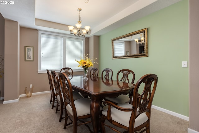 dining space featuring baseboards, light colored carpet, a raised ceiling, and a notable chandelier