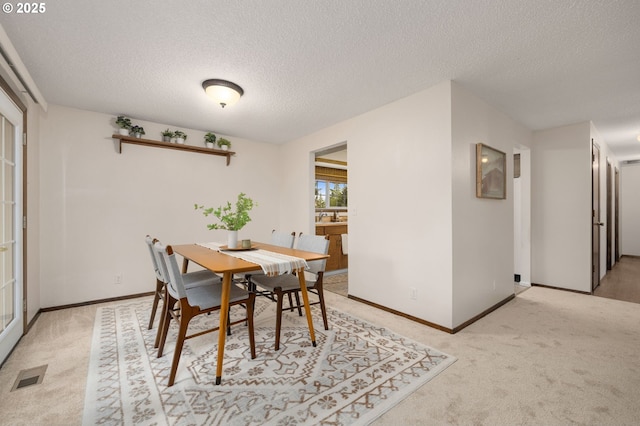 dining space featuring a textured ceiling, visible vents, and light carpet