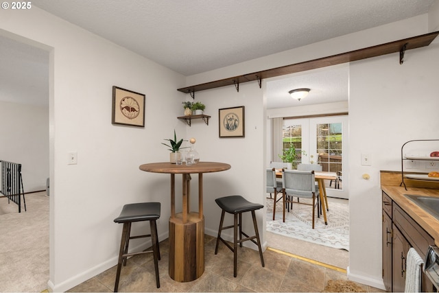 dining area featuring french doors, a textured ceiling, and baseboards