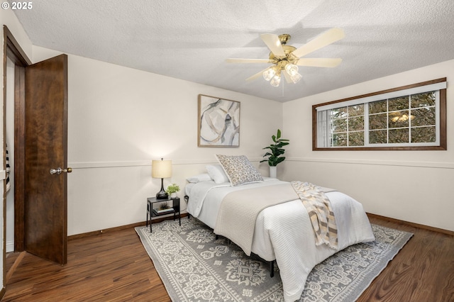 bedroom with a ceiling fan, wood finished floors, baseboards, and a textured ceiling