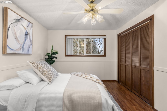 bedroom with ceiling fan, a closet, a textured ceiling, and wood finished floors