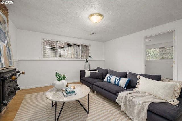 living area with visible vents, a textured ceiling, light wood-type flooring, and baseboards