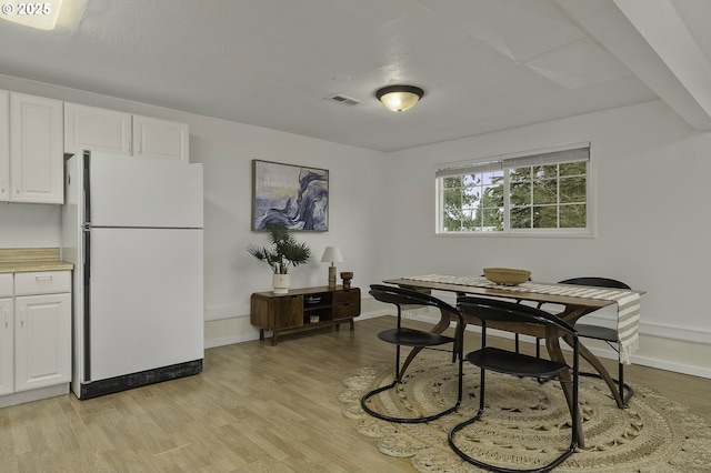 dining room featuring visible vents, baseboards, and light wood-style flooring