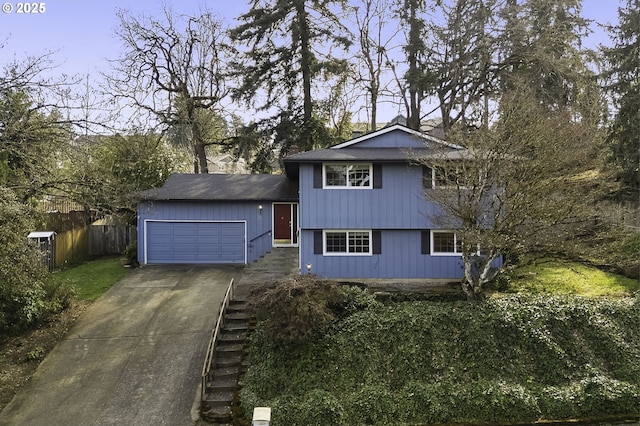 tri-level home with stairway, fence, a garage, and driveway