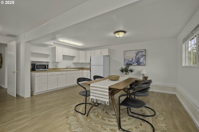 dining room with visible vents, light wood-type flooring, and baseboards