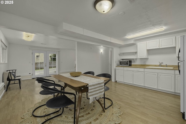 dining space with light wood finished floors and french doors