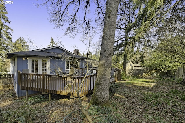 back of house with a deck, a chimney, and a fenced backyard