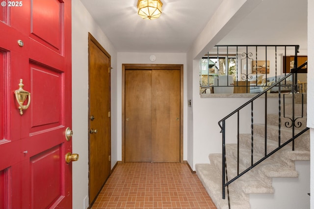 foyer entrance featuring brick floor and stairway