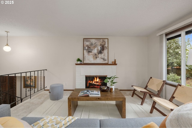 living area with a fireplace, a textured ceiling, and baseboards