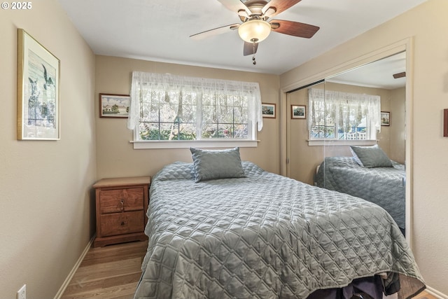 bedroom with a closet, ceiling fan, baseboards, and wood finished floors