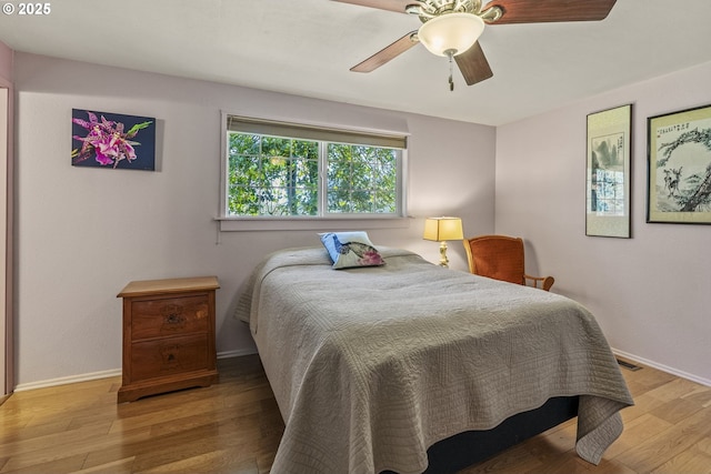 bedroom featuring a ceiling fan, visible vents, baseboards, and light wood-type flooring