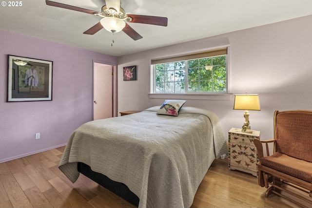 bedroom with a ceiling fan, wood finished floors, and baseboards