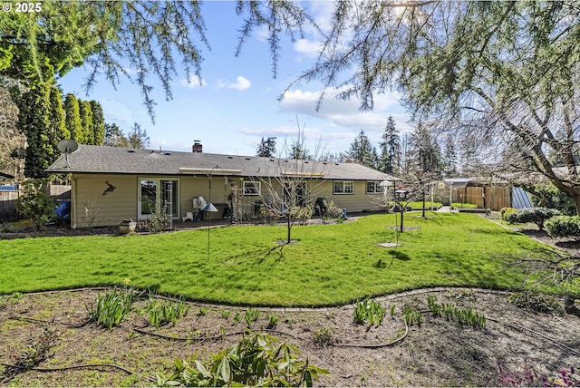 rear view of property featuring a lawn, a chimney, and fence