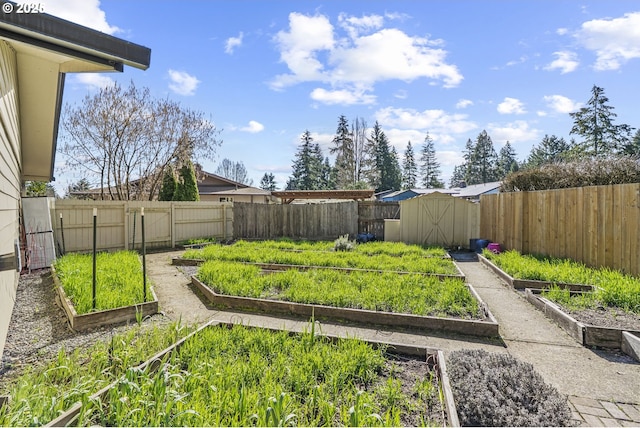 view of yard featuring an outbuilding, a storage unit, a fenced backyard, and a garden