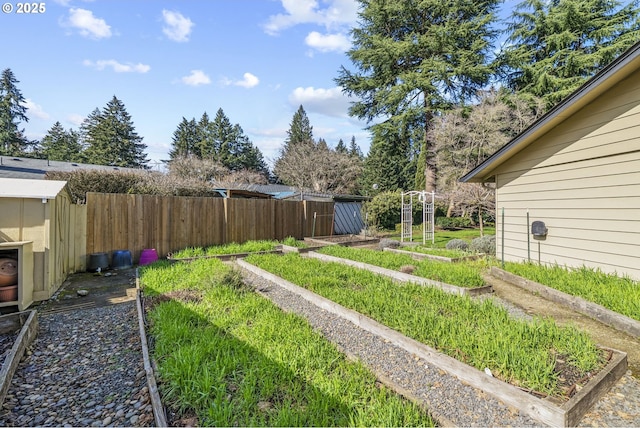 view of yard with an outdoor structure, a vegetable garden, and fence