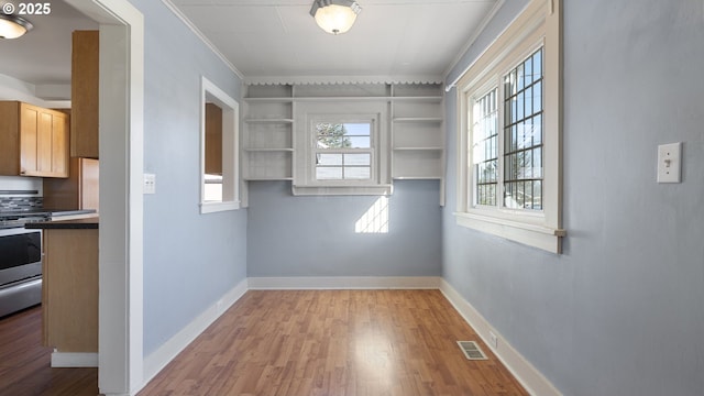 unfurnished dining area with wood finished floors, visible vents, and baseboards