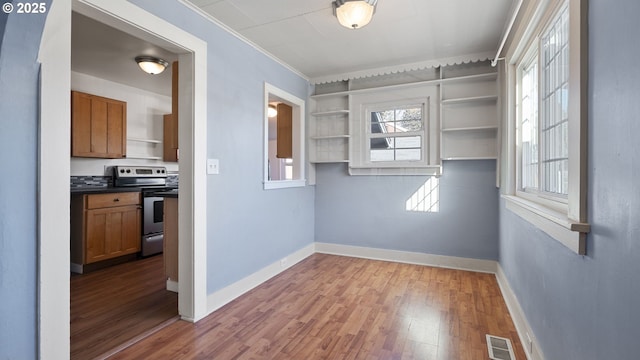 interior space with baseboards, visible vents, wood finished floors, and ornamental molding