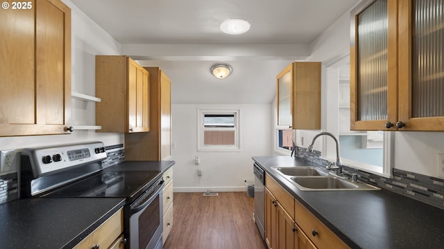 kitchen featuring appliances with stainless steel finishes, dark wood-style flooring, dark countertops, and a sink