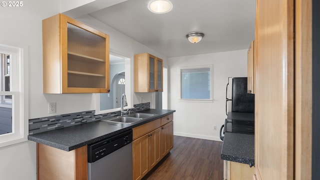 kitchen featuring dark countertops, dark wood-style floors, freestanding refrigerator, stainless steel dishwasher, and a sink