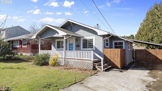 bungalow-style home featuring driveway, a porch, fence, a front lawn, and a carport