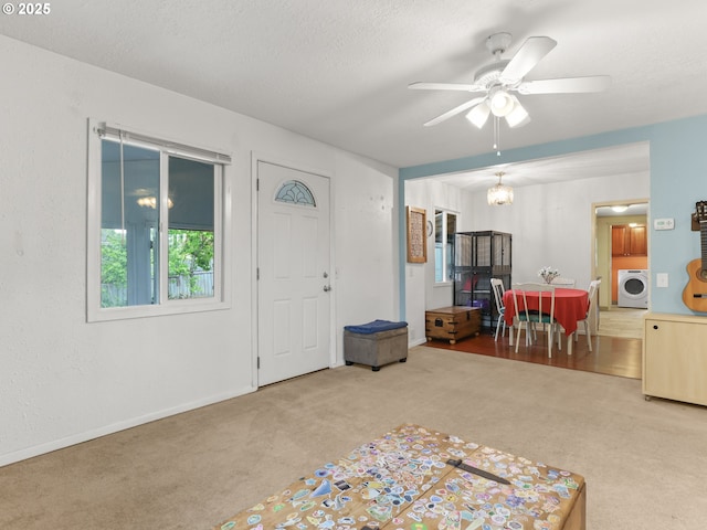 foyer featuring washer / dryer, baseboards, carpet flooring, and ceiling fan with notable chandelier