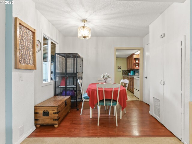 dining room featuring visible vents, a textured ceiling, wood finished floors, and a chandelier