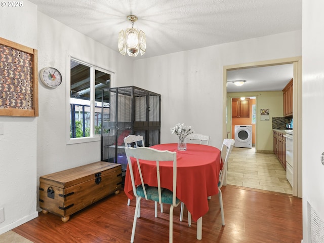 dining room featuring a chandelier, washer / dryer, and light wood finished floors