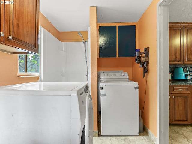 washroom with cabinet space, light tile patterned flooring, and independent washer and dryer