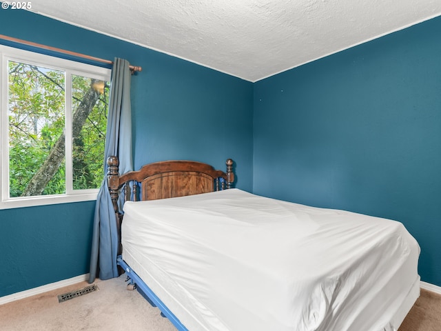 carpeted bedroom featuring a textured ceiling, baseboards, and visible vents