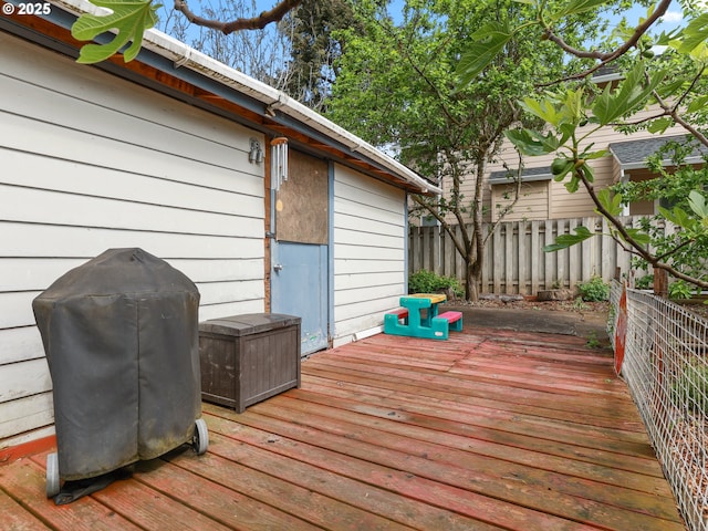 wooden terrace featuring fence and a grill