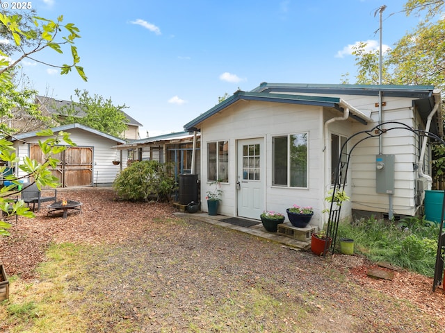 rear view of property featuring an outdoor fire pit and central AC