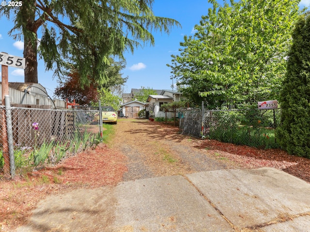 view of yard featuring dirt driveway and fence