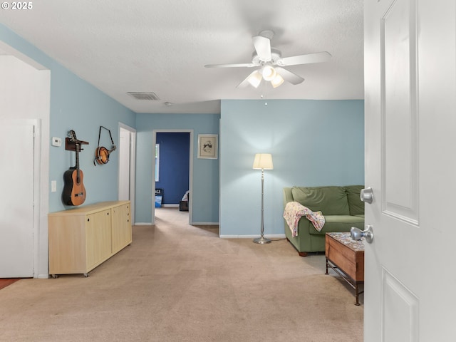 sitting room with ceiling fan, light carpet, a textured ceiling, baseboards, and visible vents