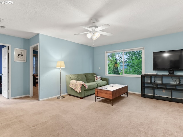 living area featuring baseboards, ceiling fan, carpet, and a textured ceiling