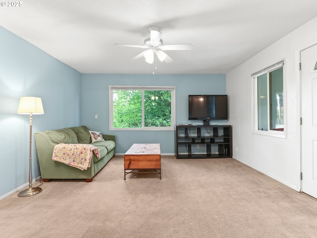 living area featuring baseboards, ceiling fan, and carpet